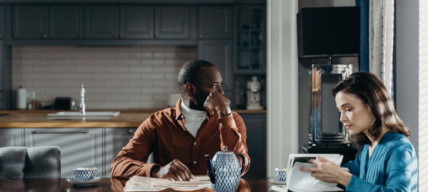 A couple at their kitchen table reading the news and reviewing their finances